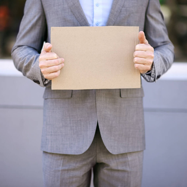 Hire me and Ill spread your message for you. a businessman holding a blank placard in the street - Photo, Image