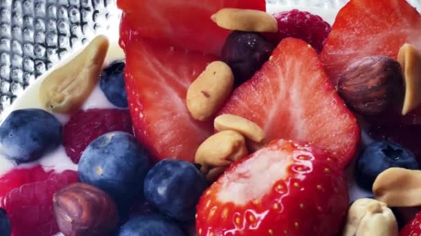 Gesundes Frühstück und Biolebensmittel, Erdbeeren, Himbeeren, Blaubeeren und Erdnüsse mit laktosefreiem Joghurt in der Schüssel, Diät und Ernährung, leckere Rezeptidee. Hochwertiges 4k Filmmaterial - Filmmaterial, Video