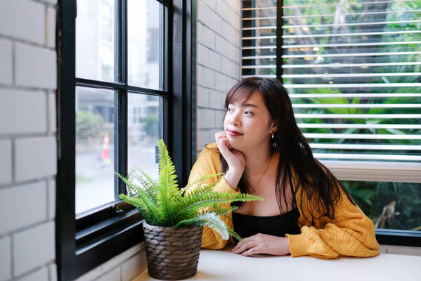 Gros plan de jeune jolie femme asiatique assise dans le café se sentant relaxer. - Photo, image