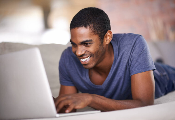 Verbonden blijven met geliefden. een knappe jonge man met behulp van zijn laptop terwijl ontspannen thuis - Foto, afbeelding