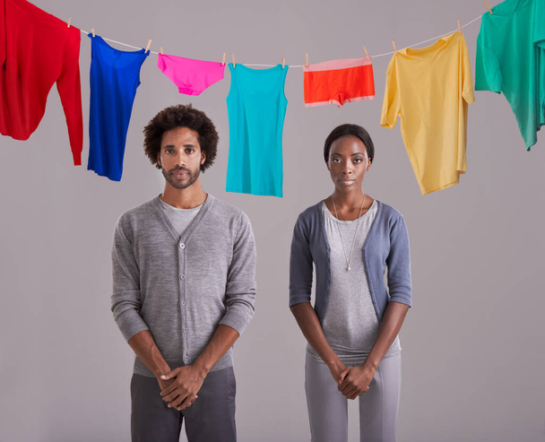 Bloccato nella routine della vita. Studio foto di una giovane coppia in piedi di fronte ad una linea di lavaggio piena di lavanderia colorata - Foto, immagini
