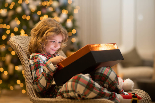 Surprise kid opening Christmas present gift box. Child at home on Christmas. Little kid celebrating Christmas or New Year - Valokuva, kuva