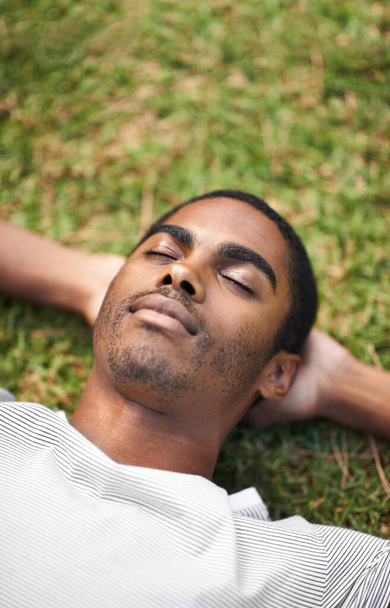 屋外での昼寝時間。屋外で草の上に寝そべっているハンサムな若者が - 写真・画像