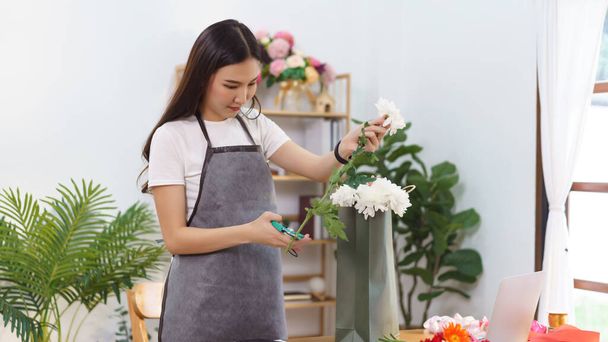 Bloemist concept, Vrouwelijke bloemist gesneden chrysant stam met schaar voor het maken van bloemboeket in de winkel. - Foto, afbeelding