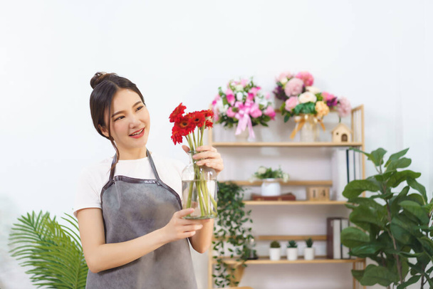 Flower shop concept, Female florist holding vase of red gerbera to prepare sending to customer. - Foto, imagen