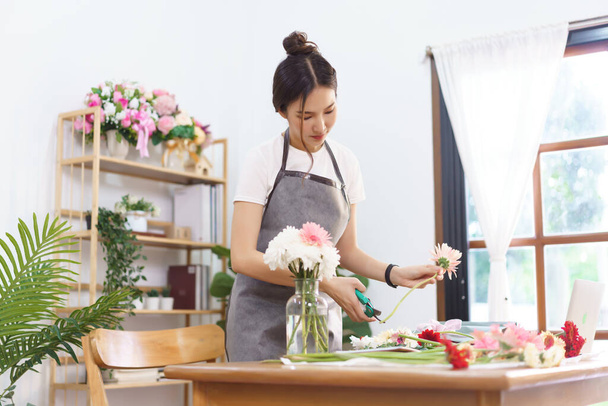 Concept de boutique de fleurs, tige fleuriste féminine de gerbera rose par ciseaux pour organiser en vase. - Photo, image