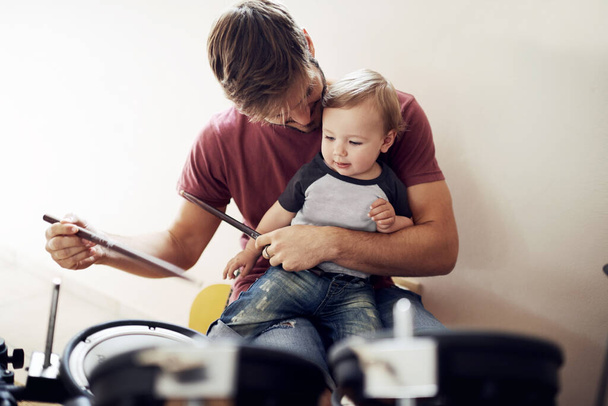 Posłuchaj... słyszysz to. Przystojny młody ojciec uczy syna grać na perkusji. - Zdjęcie, obraz