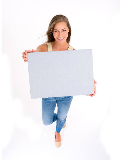 Shes got a casual confidence about her. High angle shot of a beautiful young woman holding a blank placard against a white background - Fotoğraf, Görsel