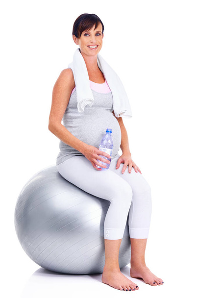 Keeping in shape, right down to her final trimester. A pregnant mother smiling with a pilates ball while isolated on white - Foto, Imagem
