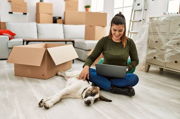 Young woman using laptop sitting on floor with dog at home - Photo, image