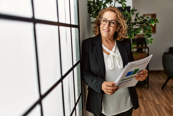 Middle age caucasian businesswoman smiling happy standing at the office. - Fotó, kép
