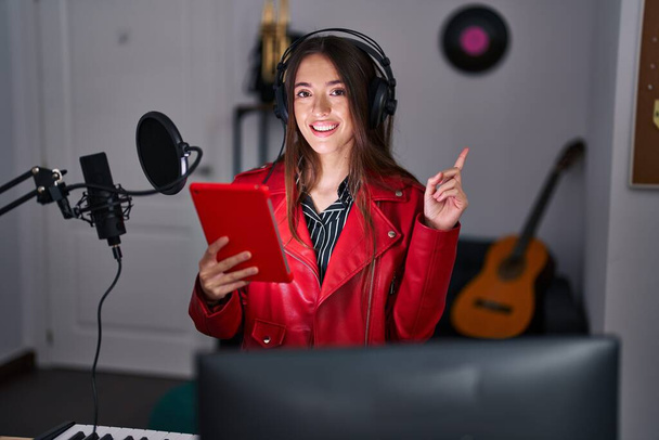 Young brunette woman singing song using microphone smiling happy pointing with hand and finger to the side  - Foto, imagen