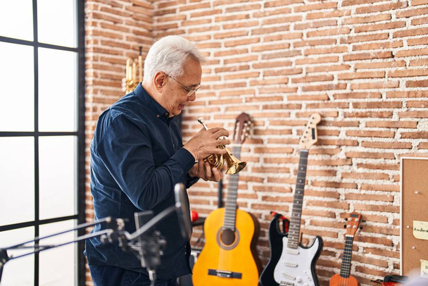 Senior man musician playing trumpet at music studio - Photo, image