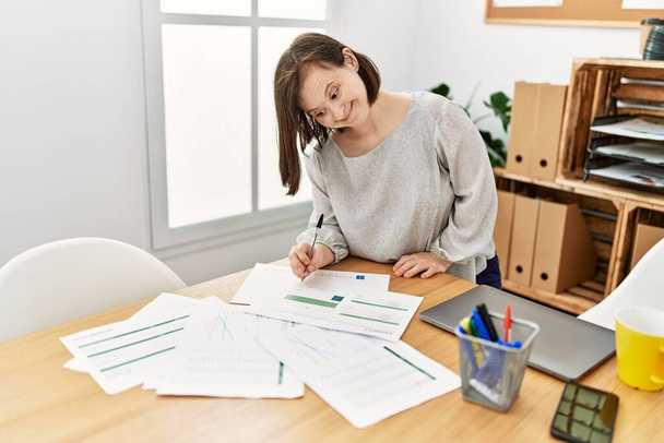 Brunette woman with down syndrome working with documents at business office - Photo, Image