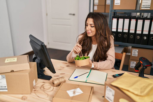 Молода іспаномовна жінка електронної комерції бізнесмен їсть салат в офісі
 - Фото, зображення