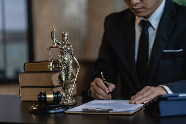 Aasialainen lakimies työskentelee taloudellisten tietojen parissa, tarkistaa rahoitustilejä ja auttaa työpöydällä työskenteleviä asiakkaita oikeudellisissa tapausasiakirjoissa työpaikalla konsultille. Laki, neuvonta ja oikeus - Valokuva, kuva