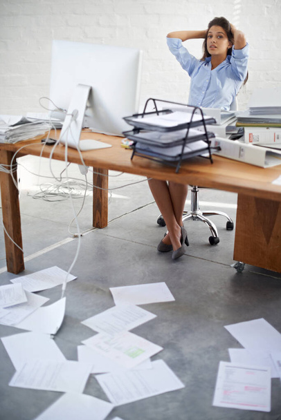Może czas się zorganizować... młoda bizneswoman siedząca przy biurku, pełna papierkowej roboty. - Zdjęcie, obraz