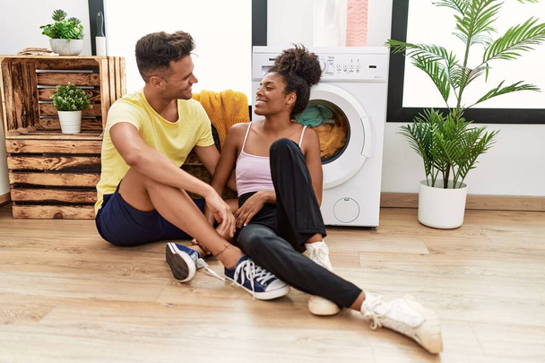 Чоловік і жінка пара обіймають один одного чекаючи пральної машини в пральні
 - Фото, зображення
