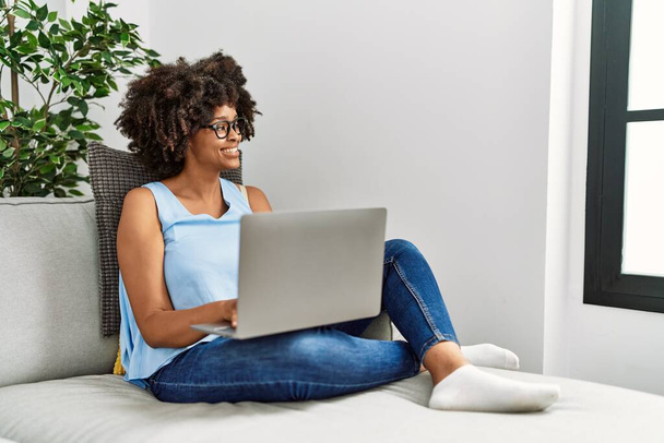 Jeune femme afro-américaine souriant confiant en utilisant un ordinateur portable à la maison - Photo, image