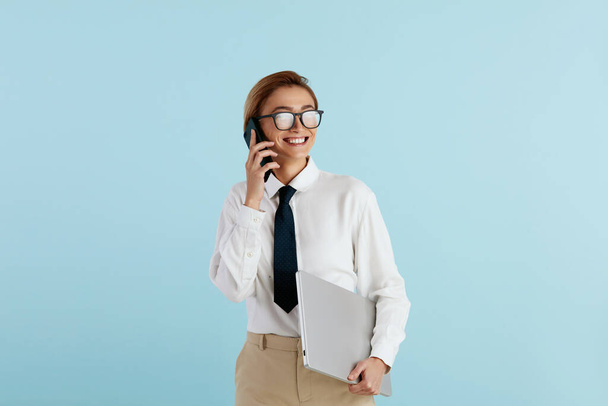 Smiling Businesswoman Talking Smartphone. Caucasian Woman Speaking on Mobile, Smiling, Holding Laptop. Modern Person Having Fun and Speaking on Call. Communication Concept - Foto, immagini