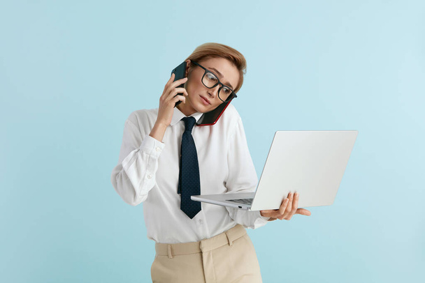 Busy Businesswoman Answering Calls Isolated. Caucasian Woman With Many Phones Feeling Stressful Holding Laptop. Lady Boss Talking Cellphone at Blue Background  - Fotoğraf, Görsel
