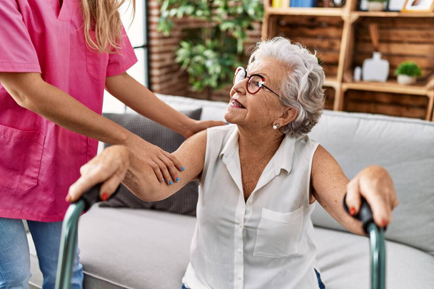 Paciente idosa de cabelos grisalhos, com suporte para enfermeiro e andador em geriatria - Foto, Imagem