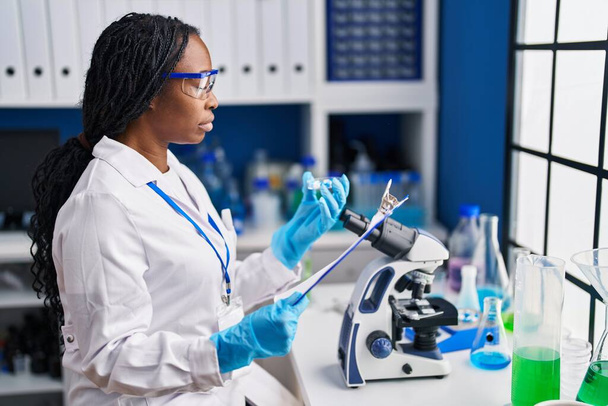 African american woman wearing scientist uniform working laboratory - 写真・画像