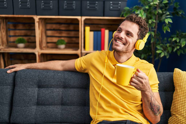 Young hispanic man listening to music drinking coffee at home - Foto, afbeelding