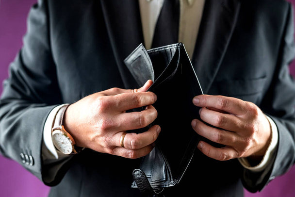 Close-up of a shocked man's hand holding an empty wallet without banknotes. the man is bankrupt. problems with finances - 写真・画像