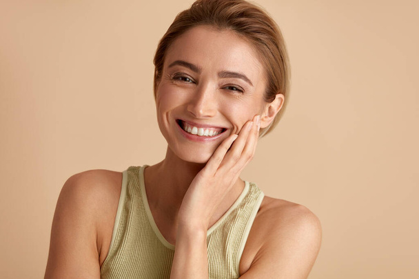 Beauty Woman Laughing Isolated Portrait. Blonde Woman Model With Smooth Skin Smiling Against Beige Background. Confident Female Enjoying Her Perfect Body After Cosmetology Treatment  - Fotó, kép