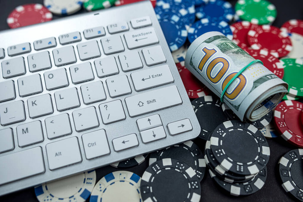 fiches da poker per poker con banconote attorcigliate posizionate sulla tastiera del laptop. isolato su sfondo nero. Concetto Poker - Foto, immagini