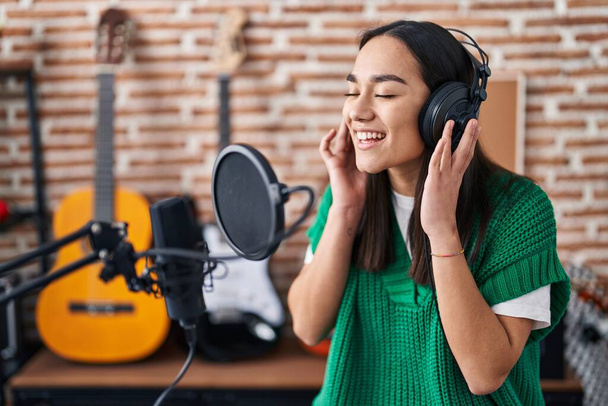 Young hispanic woman musician singing song at music studio - Photo, Image