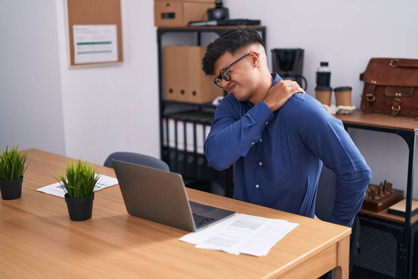 Giovane uomo d'affari ispanico che soffre di mal di schiena che lavora in ufficio - Foto, immagini