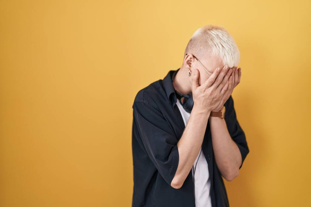 Young caucasian man wearing sunglasses standing over yellow background with sad expression covering face with hands while crying. depression concept.  - Photo, Image