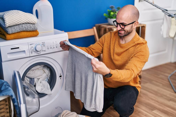 Giovane uomo sorridente fiducioso lavare i vestiti in lavanderia - Foto, immagini