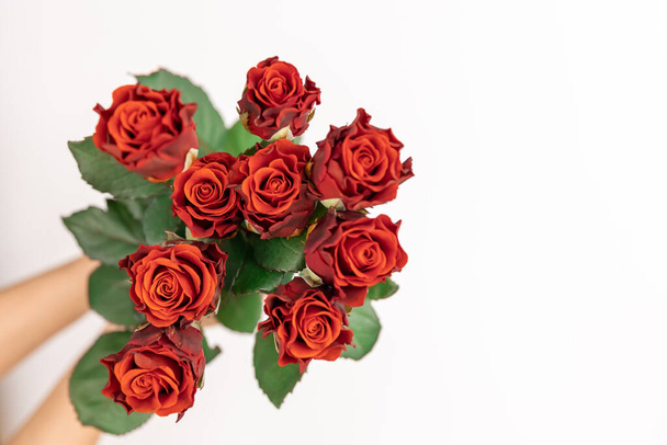 Kytice z rudých růží v ženských rukou na bílém pozadí, horní pohled, kopírovací prostor. - Fotografie, Obrázek
