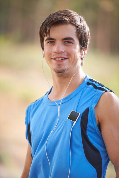 Theres nothing like fresh air and exercise. Portrait of a young male runner listening to music on his mp3 player - Photo, Image