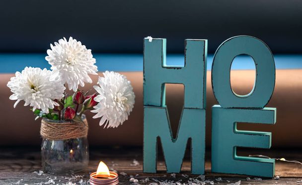 Gemütliche Komposition mit dekorativem Wort Heimat, Blumen und Kerze auf verschwommenem Hintergrund. - Foto, Bild