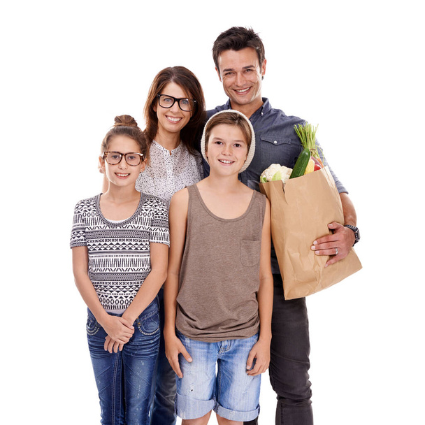 Theyre trendy, modern and in touch with eco-friendly living...the perfect hipster family. A trendy family holding a bag of fresh produce together against a white background - Fotografie, Obrázek
