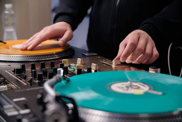 Hip hop dj scratches vinyl record on turn table. Disc jockey scratching vinyls on turntables in sound recording studio - 写真・画像