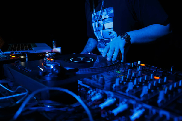 Hip hop dj scratching records on turntables. Disk jokey scratches vinyl record on turntable in nightclub. Professional disc jockey mixing music on party in night club - Photo, image