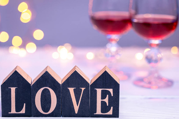Decorative word love on a blurred background with glasses of wine and bokeh. - Foto, Imagen