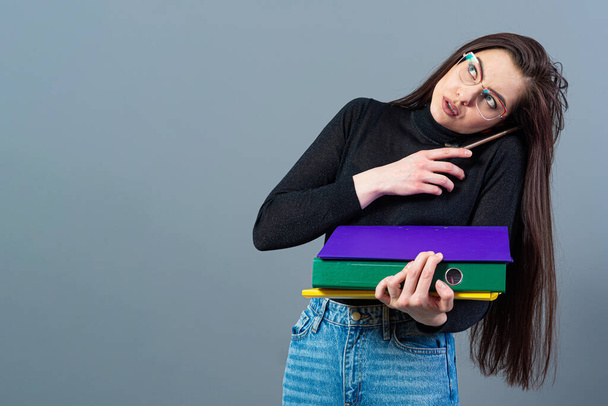 woman with smartphone holding a colorfuls folders with documents, isolated on dark background - Fotó, kép