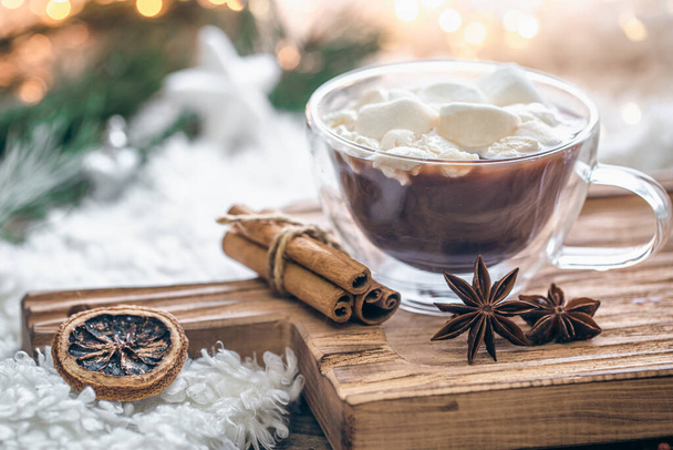 A cup of cocoa, cinnamon and star anise on a blurred background with bokeh, copy space. - 写真・画像