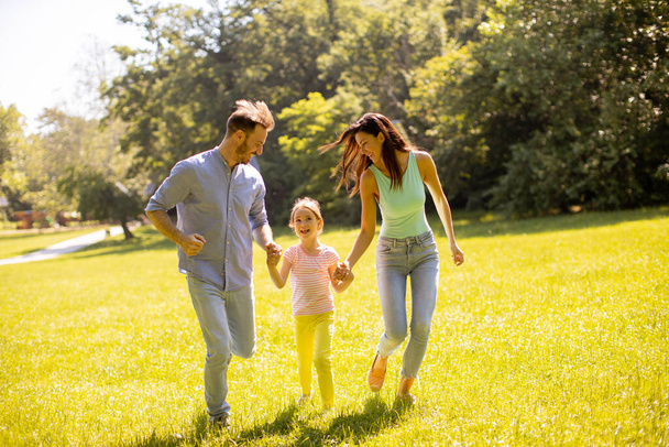 Glückliche junge Familie mit süßer kleiner Tochter, die an einem sonnigen Tag Spaß im Park hat - Foto, Bild