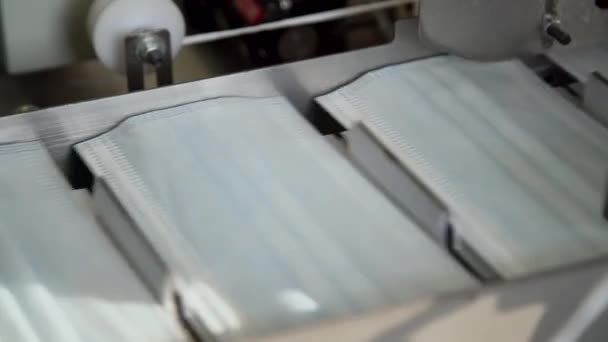 Closeup proces van medische gezichtsmaskers wordt gemaakt in een fabriek. Geautomatiseerde machines voor het vervaardigen van medische maskers voor de ademhaling in grote hoeveelheden.  - Video