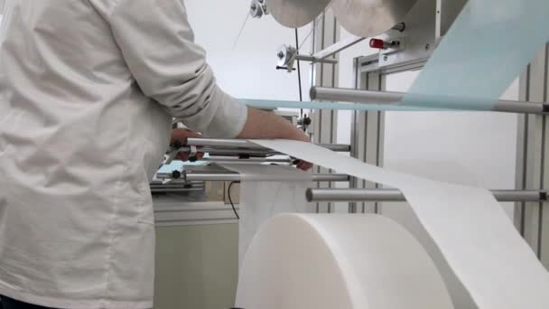 Close-up van medewerkers handen met uitzicht op het proces van het maken van medische maskers in een fabriek.  - Video