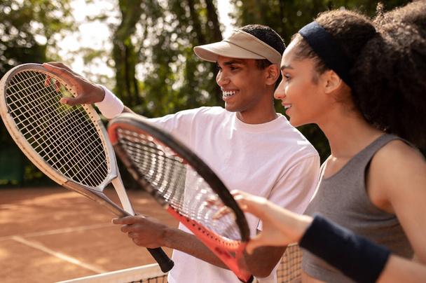 Workout. Young male coach teaching a curly-haired girl to play tennis - Foto, Bild