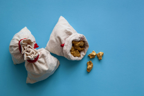 Sacks of gold nuggets on a blue background. - Photo, Image