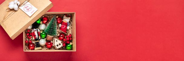 Χειροποίητο πακέτο φροντίδας, εποχιακή συσκευασία δώρου με παιχνίδια, Χριστουγεννιάτικη διακόσμηση σε κόκκινο τραπέζι Εξατομικευμένο οικολογικό καλάθι για οικογένεια, φίλους, κορίτσι για 24 Δεκεμβρίου, Χριστούγεννα, Πρωτοχρονιά Flat lay. - Φωτογραφία, εικόνα